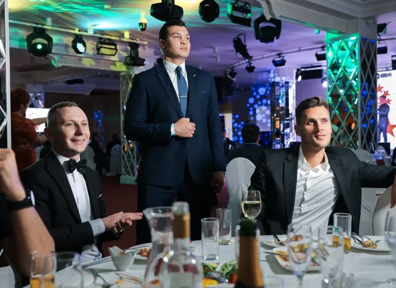 Man in a suit beside seated event guests